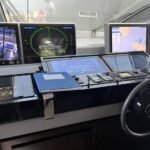 Vista de una cabina de navegación moderna con múltiples pantallas que muestran datos del piloto automático, radar y mapas electrónicos.