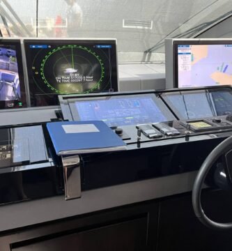 Vista de una cabina de navegación moderna con múltiples pantallas que muestran datos del piloto automático, radar y mapas electrónicos.