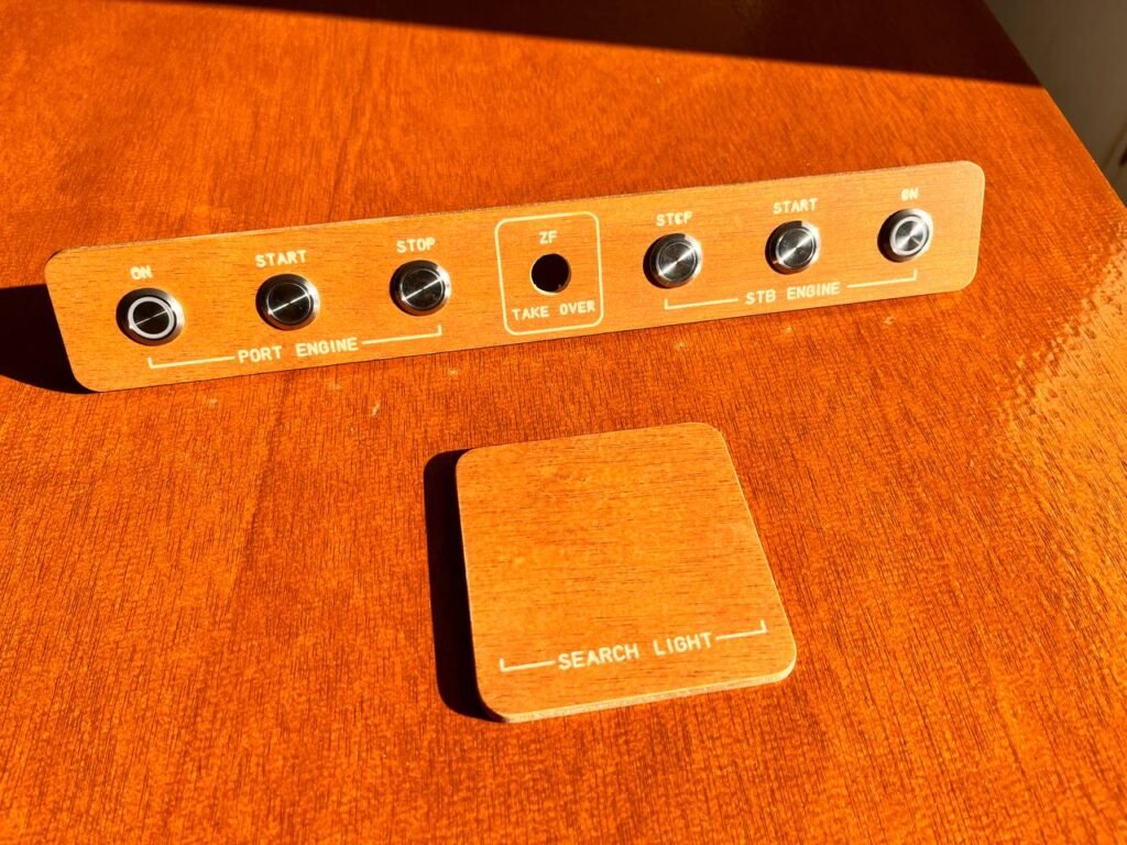 Panel de control de embarcación con botones para encender, iniciar y detener motores, junto con control de luz de búsqueda, fabricado con diseño ergonómico y materiales resistentes al agua.