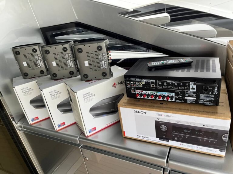 Vista de un sistema de audio inalámbrico compuesto por múltiples altavoces y un receptor Denon destinado a uso en embarcaciones.