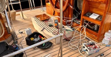 Imagen de un área de trabajo en una embarcación, mostrando herramientas de electrónica, un multímetro, y conexiones eléctricas en proceso de instalación.