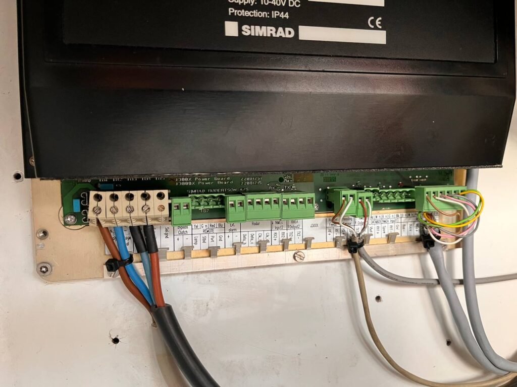 Visualización del panel de conexiones del piloto automático Simrad J300X, incluyendo terminales y cableado, para diagnóstico técnico.
