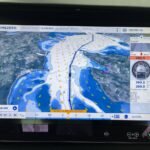 Pantalla de un sistema de navegación TimeZero mostrando un mapa con rutas, información meteorológica y datos de navegación.. TimeZero, .