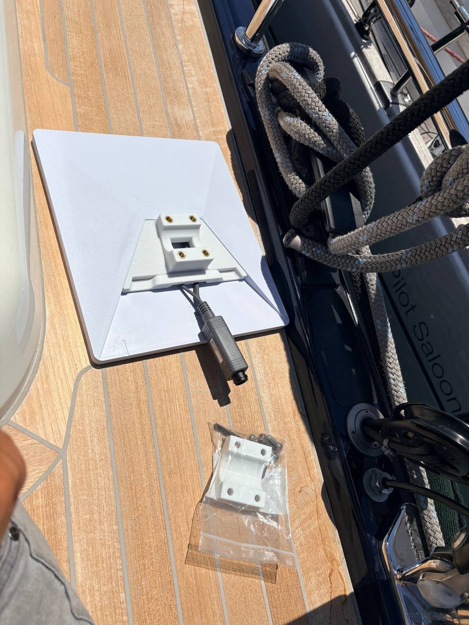 Starlink flat antenna on a teak yacht deck with mounting bracket, cable and marine rigging nearby